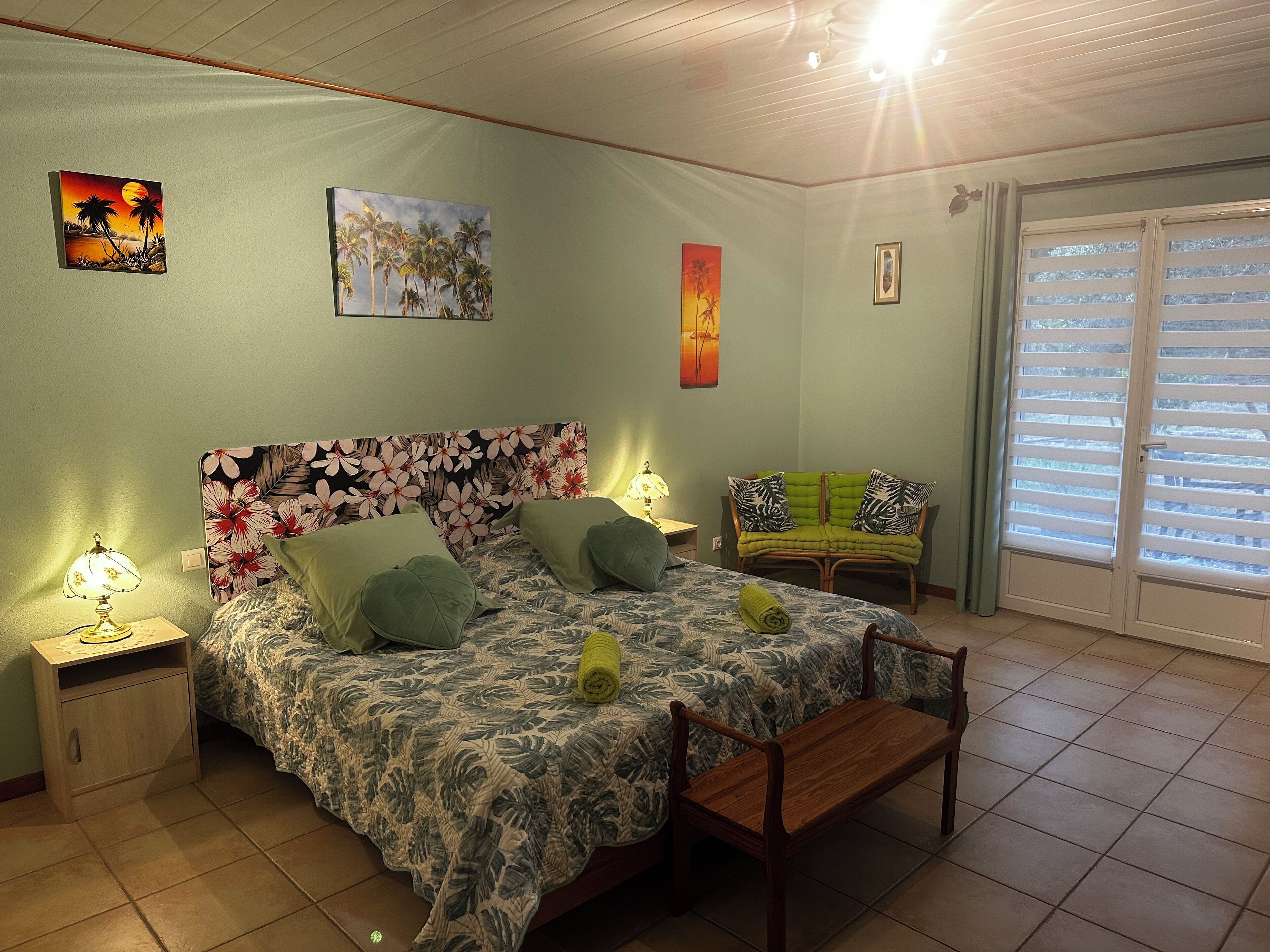 A bedroom with a bed, a nightstand, a chair, and a window with blinds.