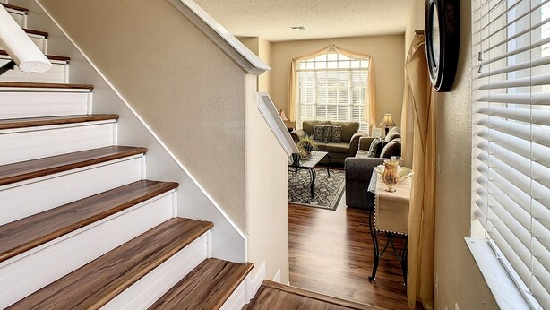 A staircase leading to a living room with a sofa, a coffee table, and a window with blinds. - Triton Vacation Pool Home Near Disney (Clermont)