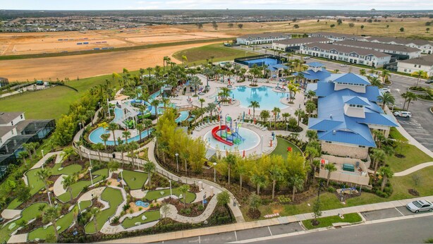 Eine Vogelperspektive zeigt ein Resort mit einem zentralen Pool, mehreren Wasserrutschen und einem Golfplatz.