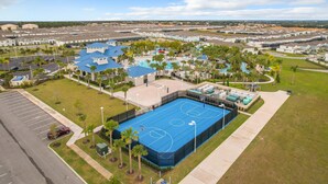 Eine Vogelperspektive eines Wohngebiets mit einem großen, blauen Basketballplatz, umgeben von viel Grün, und einem Schwimmbad.