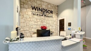 Eine Rezeption im Windsor Island Resort mit Backsteinwand, einem Blumentopf und einem Schild über dem Empfangsbereich.