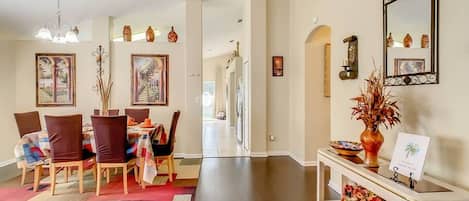 A spacious dining area with a long table, chairs, and a chandelier.