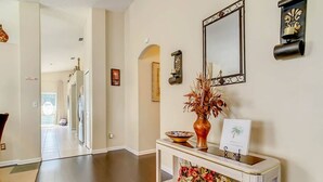 A hallway with a white console table, a mirror, and a vase with dried flowers. - Flounder Vacation Home (Clermont)