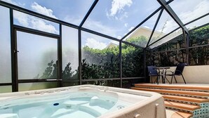 A hot tub in a covered outdoor area with a view of greenery and a clear sky. - Flounder Vacation Home (Clermont)