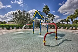 A water play area with a blue and yellow structure, surrounded by lounge chairs and palm trees. - Flounder Vacation Home (Clermont)