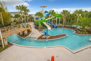 A pool area with a water slide, palm trees, and a wooden bridge. - Windsor Island Vacation Pool Home (Davenport)