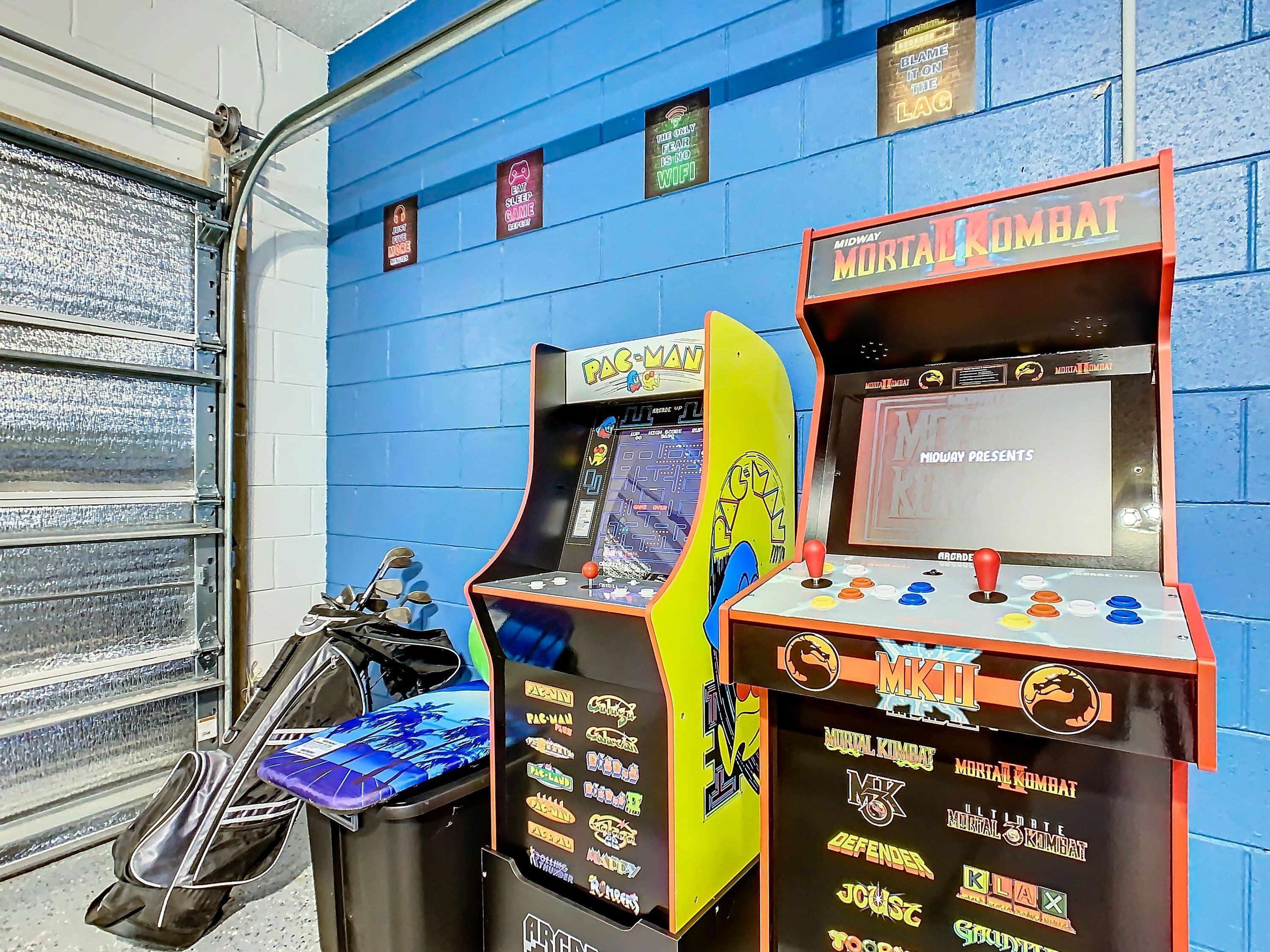 Arcade machines, including Pac-Man and Mortal Kombat, against a blue wall.