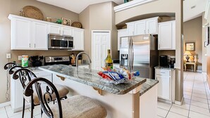 A modern kitchen with white cabinets, stainless steel appliances, and a marble island. - Sebastian Pool Villa W Spa (Clermont)