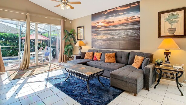A living room with a sofa, coffee table, and a large window overlooking a garden. - Sebastian Pool Villa W Spa (Clermont)