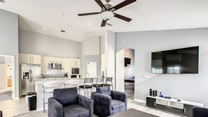 Een moderne woonkamer met grijze banken, een salontafel en een aan de muur bevestigde televisie.