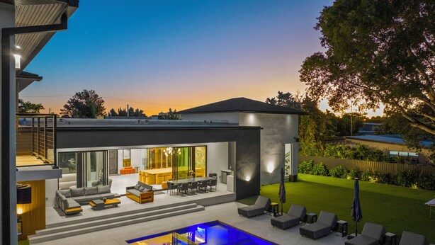 Ein modernes Haus mit Swimmingpool, Sitzgelegenheiten im Freien und einer gut beleuchteten Terrasse.