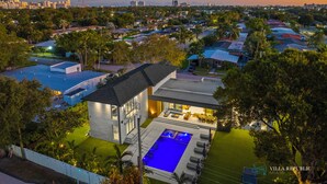 Eine moderne Villa mit Swimmingpool, umgeben von üppiger Vegetation und Blick auf die Skyline der Stadt.