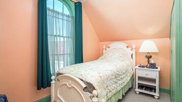 Une chambre à coucher avec un lit, une table de chevet, une lampe et une fenêtre avec des rideaux.