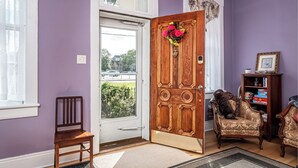 Une pièce avec une porte en bois, une chaise, un canapé et une bibliothèque.