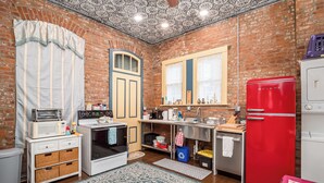 Une cuisine de taille réduite, avec un réfrigérateur rouge, un four à micro-ondes, une cuisinière et un évier.