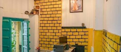 A narrow hallway with a brick wall, a wooden cabinet, and a door with green shutters.