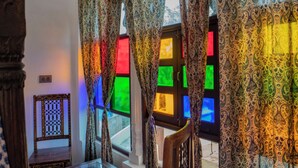 A room with patterned curtains, a wooden chair, and a glass table. - Soham Haveli Udaipur (Udaipur)