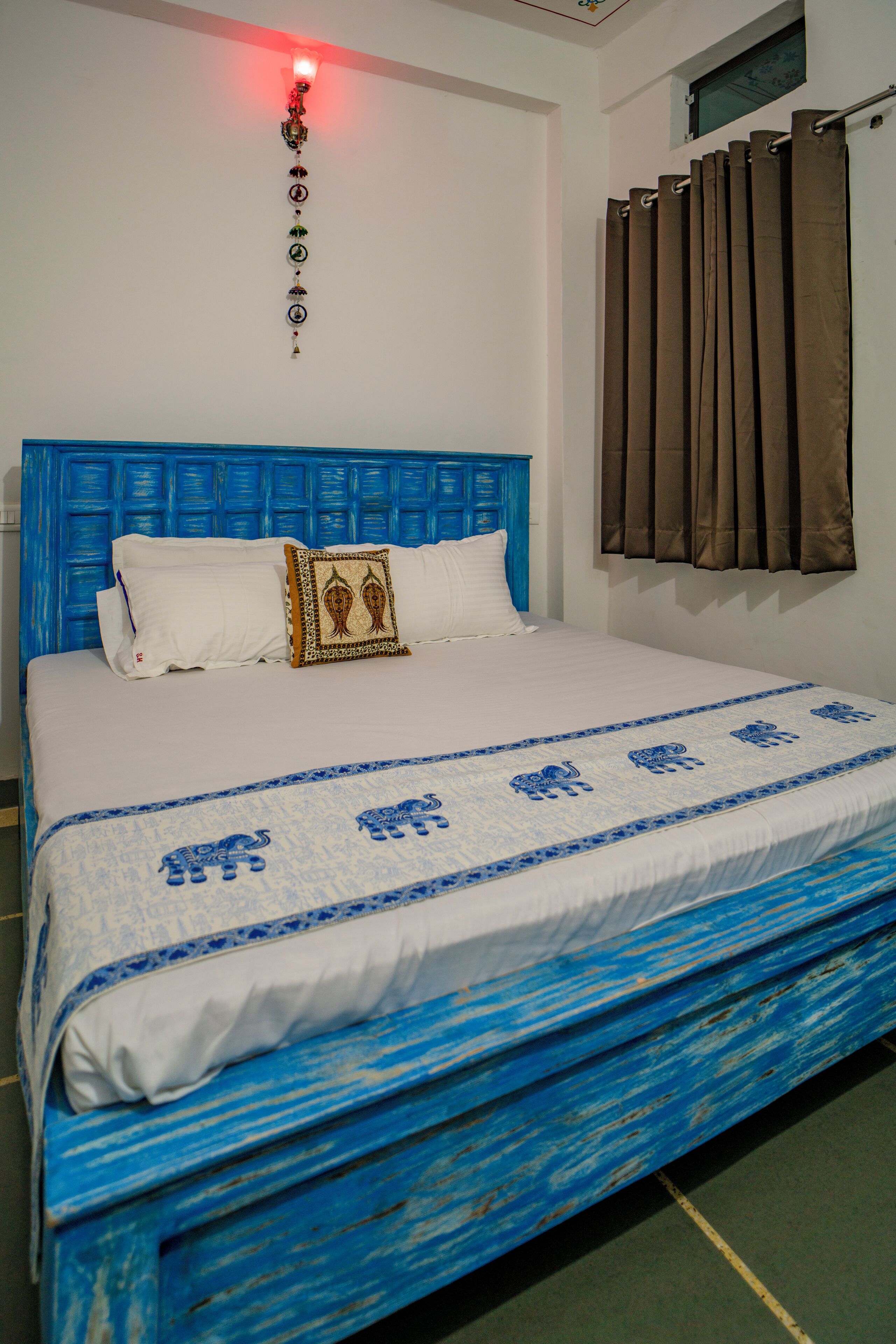 Una cama con cabecera azul, ropa de cama blanca y un cojín decorativo.