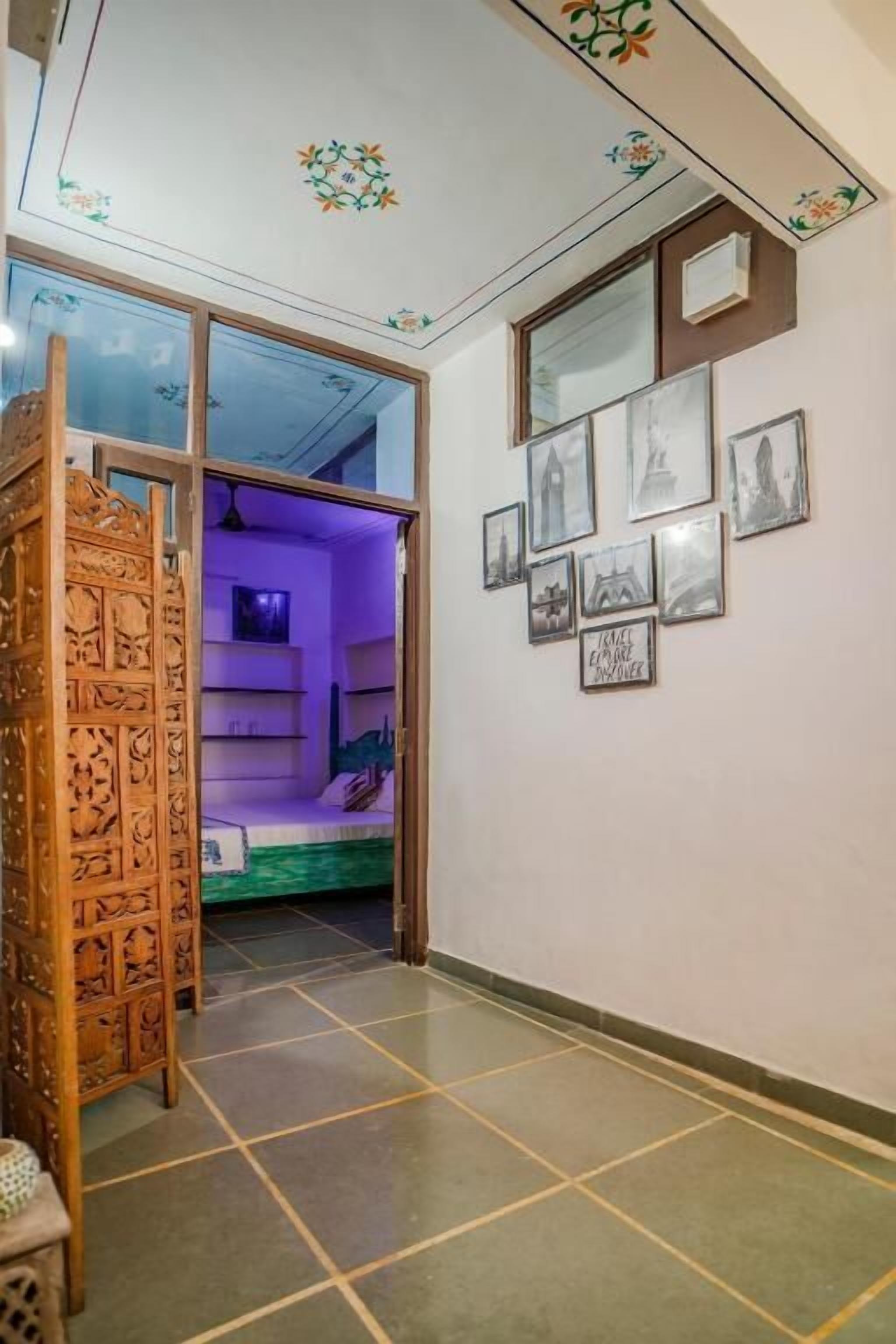 A room with a bed, a wooden cabinet, and a wall with framed pictures.