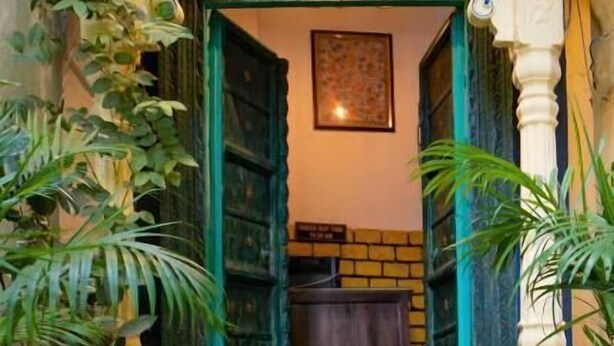 An entrance with a decorative archway, a green mat, and potted plants. - Soham Haveli Udaipur (Udaipur)
