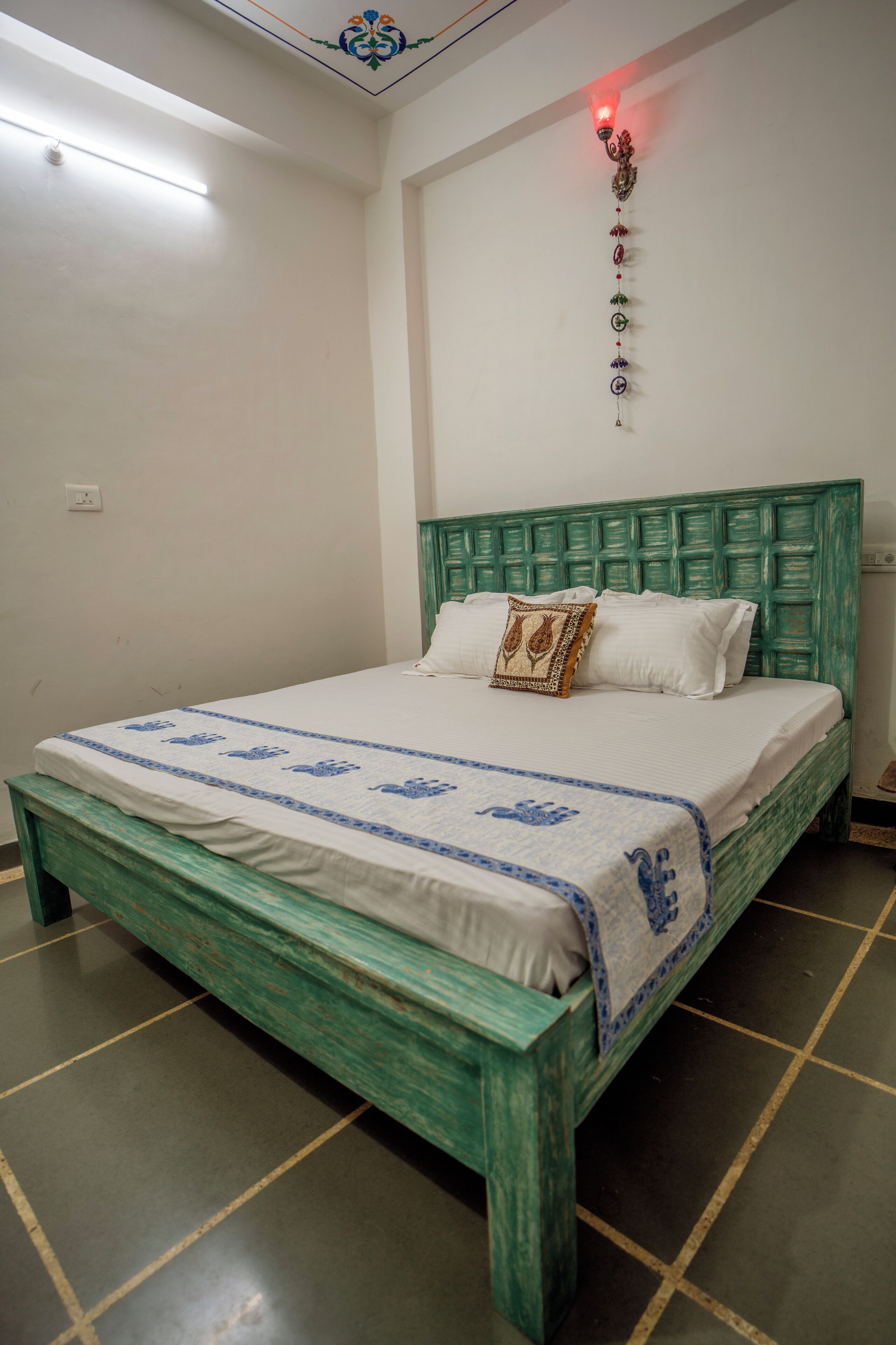 Ein Schlafzimmer mit einem grünen Kopfteil, einer weißen Bettdecke und einem Wandbehang.