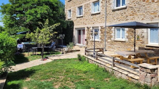 A stone building with multiple windows and a patio area with outdoor seating. - l Aurigast (Auriac-Lagast)