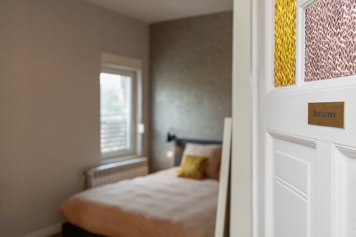 Un dormitorio con cama, ventana y puerta con un cartel.
