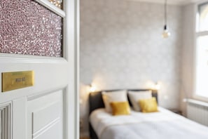 A hotel room with a bed, a bedside table, and a window.