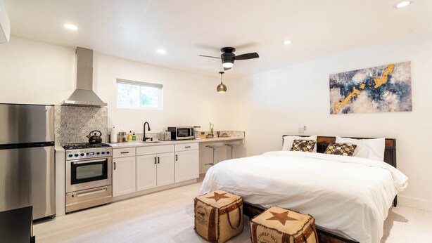 A modern bedroom with a large bed, a ceiling fan, and a kitchen area with a stove and refrigerator. - 'The Sweet Pad' - Cozy Studio with WiFi and AC in lovely Ojai (Ojai)