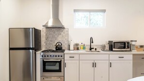 A modern kitchen with stainless steel appliances, a gas stove, a built-in oven, and white cabinetry. - 'The Sweet Pad' - Cozy Studio with WiFi and AC in lovely Ojai (Ojai)
