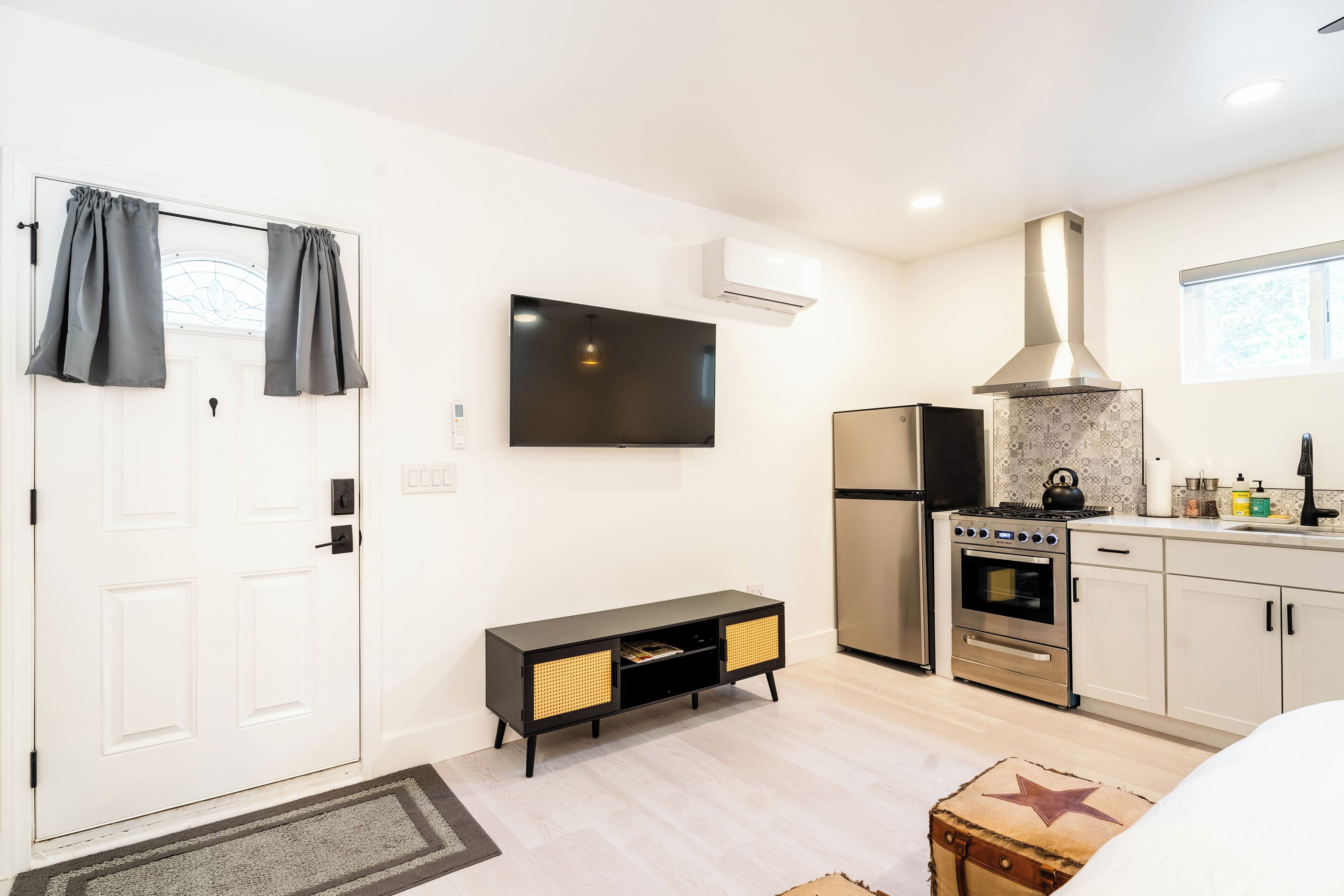 A modern kitchen with a built-in oven, a stainless steel range, and a large window.