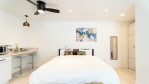 A modern bedroom with a bed, a ceiling fan, a kitchen area with bar stools, and a bathroom with a mirror. - 'The Sweet Pad' - Cozy Studio with WiFi and AC in lovely Ojai (Ojai)