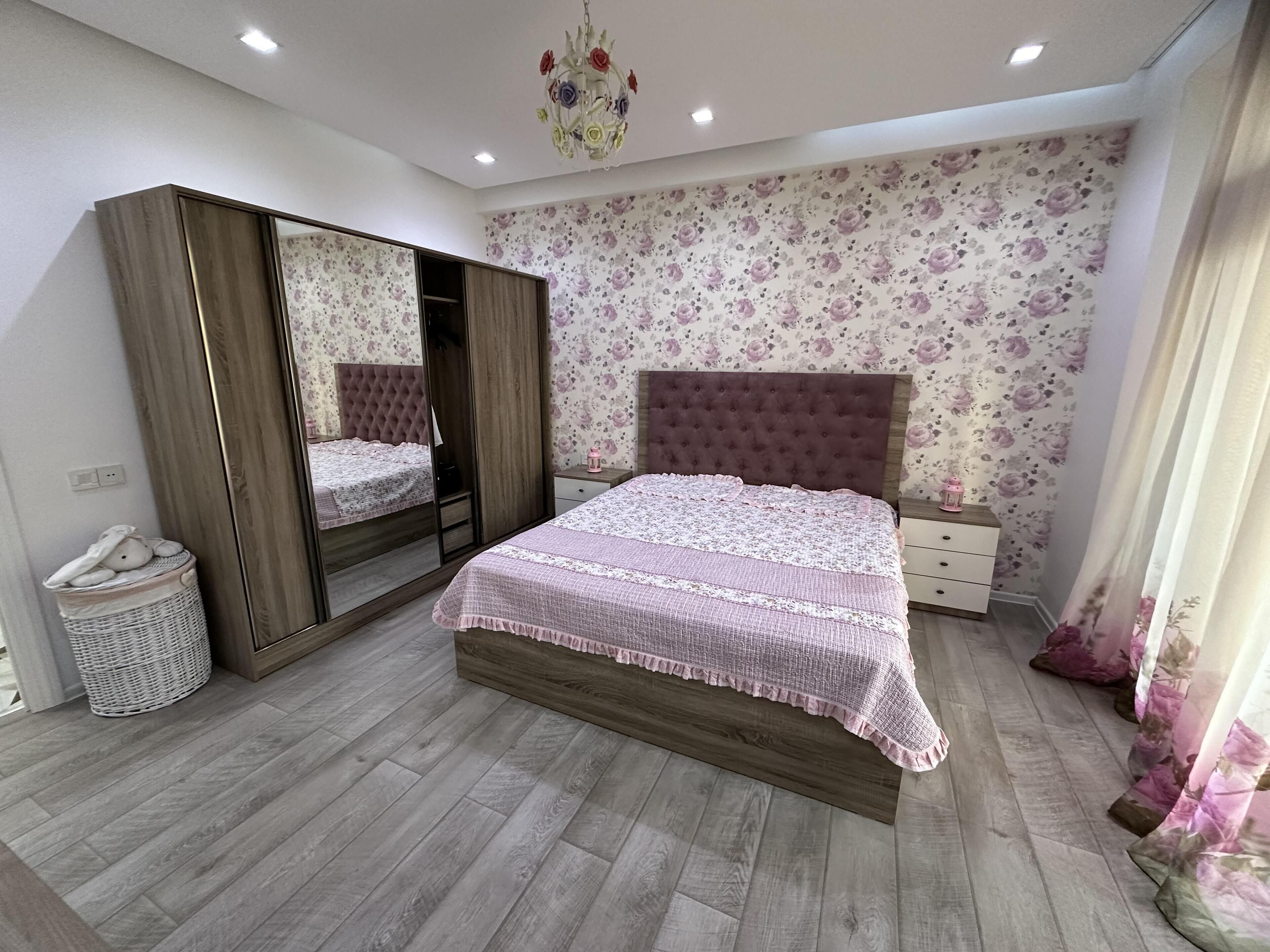 Une chambre à coucher avec un grand lit, une armoire, une table de chevet et un miroir.