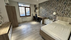 A modern bedroom with a large bed, a desk, a wardrobe, and a radiator. - Charming 2-bed Apartment in Baku City Center (Baku)