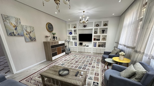 A modern living room with a sofa, armchair, coffee table, and a patterned rug. - Charming 2-bed Apartment in Baku City Center (Baku)