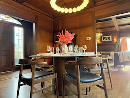 A dining area with a wooden table set for four, surrounded by chairs.