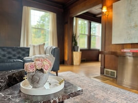 A living room with a marble coffee table, a vase of pink roses, a grey stone centerpiece, and a grey sofa.