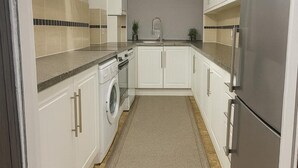 A kitchen with white cabinets, a stainless steel refrigerator, and a washing machine.