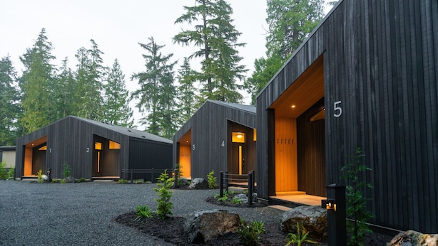 Un bâtiment moderne avec des chambres numérotées, une allée gravillonnée et des arbres tout autour.