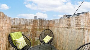 Un balcon avec deux chaises en fil de fer noir et une clôture en bambou.