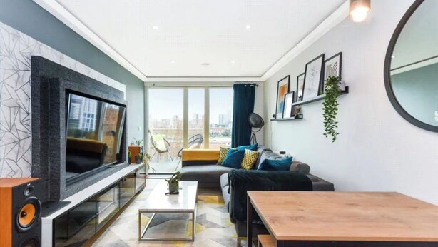 Un salon moderne avec une grande télévision, un canapé, une table basse et une table à manger.