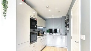 Une cuisine moderne avec des meubles blancs, un four encastré et un four à micro-ondes.