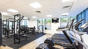 Une salle de sport équipée de machines de cardio, d’appareils de musculation et de poids libres.