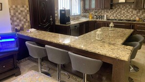 A modern kitchen with granite countertops, bar stools, and a built-in island.