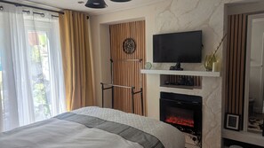 Relax in a spacious room with a large bed, modern fireplace, and flat-screen TV.