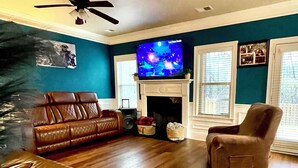 A living room with a leather sofa, a brown armchair, a television, and a fireplace.