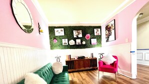 A room with a green sofa, a red chair, a wooden cabinet, and a green wall with framed pictures.