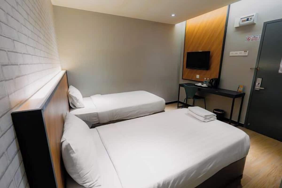 Hotellihuone, jossa on kaksi sänkyä, työpöytä, televisio ja vaatekaappi.