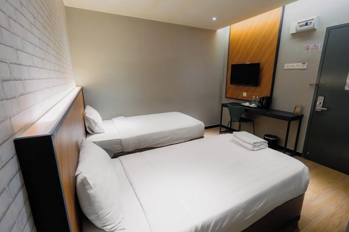 Une chambre d’hôtel avec deux lits, un bureau, une télévision et une armoire.