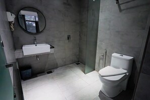 Un baño moderno con un lavamanos blanco, un inodoro y una cabina de ducha de vidrio.